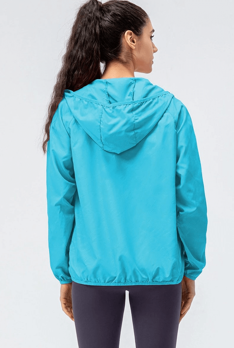 Woman wearing a blue waterproof windbreaker with hood and zipper, ideal for outdoor running. SF0136 women's sports jacket.